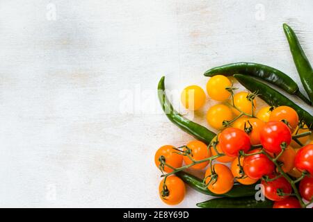 Green chilli peppers and colorful cherry tomatoes on the white background, vegetables Stock Photo