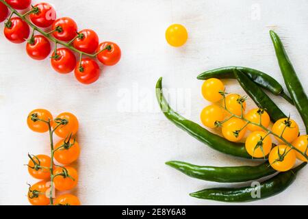 Green chilli peppers and colorful cherry tomatoes on the white background, vegetables Stock Photo