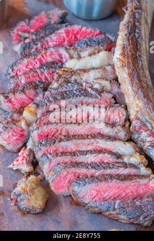 Dry-aged marble beef steak Tomahawk on wooden board with spices. Close-up, dinner concept. Stock Photo