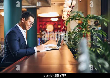 Businessman in spectacles taking notes with a ball-point pen Stock Photo