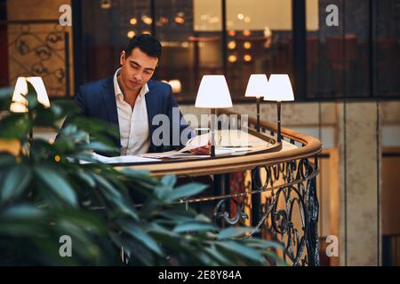 Serene young male entrepreneur leaning over a pile of papers Stock Photo