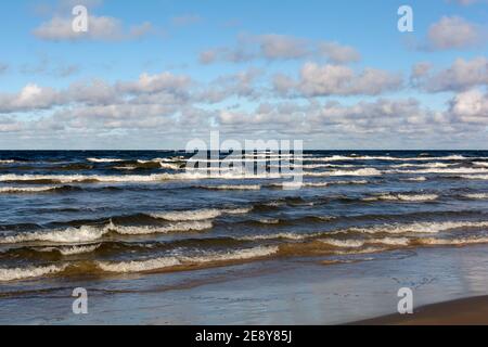 White cumulus clouds in sky over wavy Baltic sea water landscape. Many small clouds above sea.