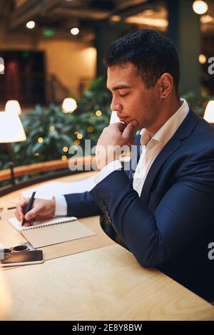Handsome dark-haired businessman taking notes on paper Stock Photo