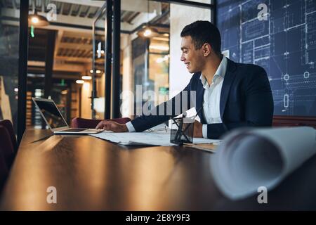 Joyful young draftsman making an engineering drawing Stock Photo