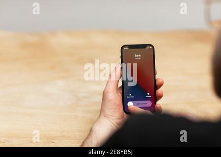 Spoofing attack by a scammer. A man answering his cell phone while his bank is calling. Fake spoofed number of the criminal trying to do a phishing at Stock Photo