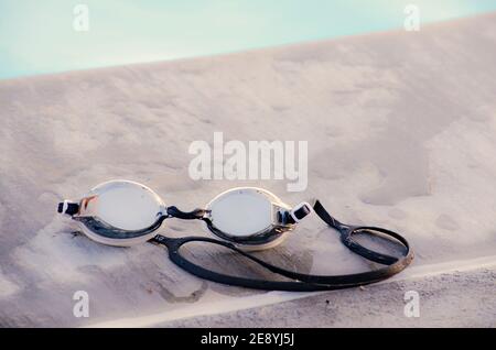 Pair of swimming goggles on side of swimming pool. Stock Photo