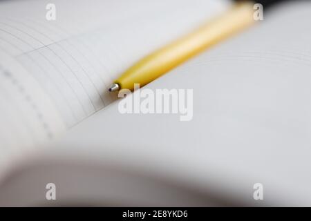 Yellow ballpoint pen lying on notebook closeup Stock Photo