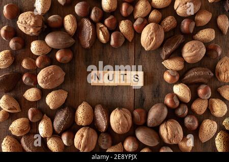 Shelles almonds, walnuts, macadamia nuts, pecans, hazelnuts arranged in a circle on wooden background Stock Photo