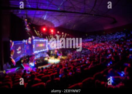 Blurred background of esports event at big arena with a lot of lights and screens. Stock Photo