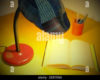 table lamp with a Sicilian coppola-type cap resting on top illuminates a book Stock Photo