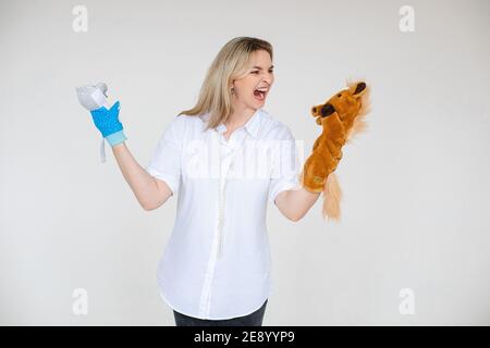 Angry girl shouting at puppet toy with pearl beads shouting at puppet horse on her left arm while wearing puppet bear on right arm.. Stock Photo