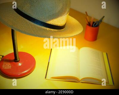 table lamp with a Panama hat resting on top illuminates a book Stock Photo