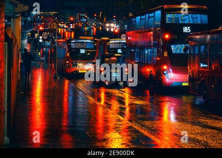 London, United Kingdom - February 01, 2019: Buses and taxis stuck in heavy traffic on a rainy evening near Lewisham station, bright red lights reflect Stock Photo