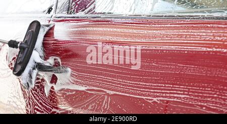 Red car washed in self serve carwash , detail on brush leaving strokes on side door, empty space for text right side Stock Photo