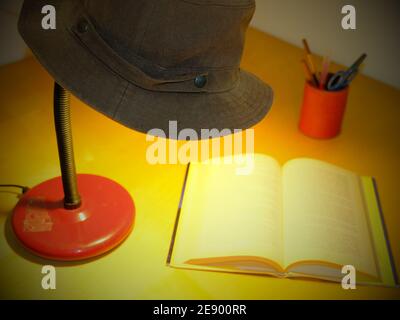 table lamp with a cowboy hat resting on top illuminates a book Stock Photo