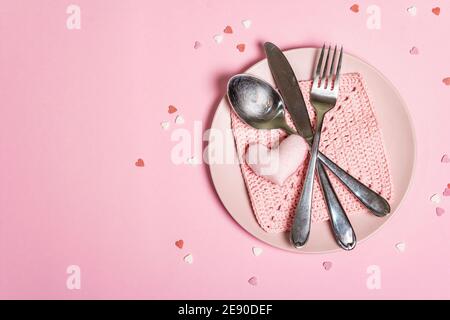Romantic dinner table. Love concept for Valentine's or mother's day, wedding cutlery. Minimalistic style, rose plates, crochet napkin, scattered pastr Stock Photo