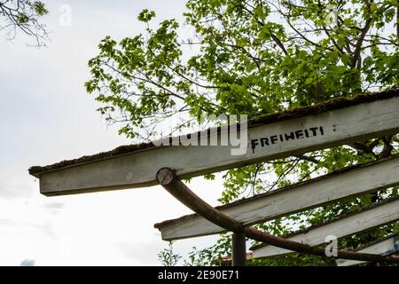 Sign on wooden constructure saying "Freiheit" (freedom in english) against sky and tree Stock Photo