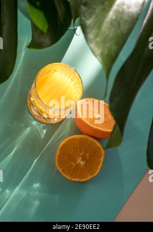 Glass of fresh squeezed orange juice isolated on turquoise blue background and rays of sunlight Stock Photo