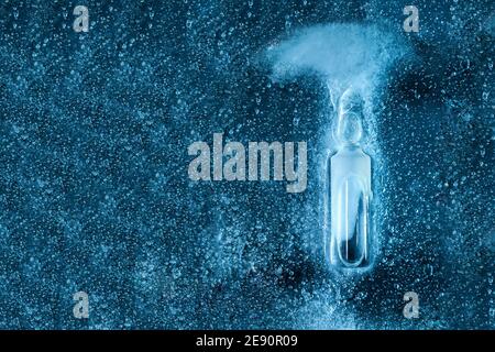 glass ampoule with corona virus vaccine filled with medicinal liquid of pharmaceutical origin on frozen ice top view, close-up of the drug on a medica Stock Photo