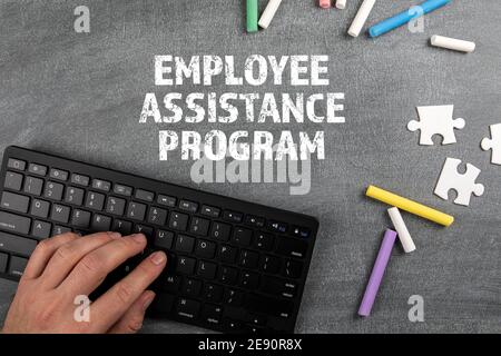 Employee Assistance Program. Computer keyboard and chalk pieces on a chalk board. Stock Photo