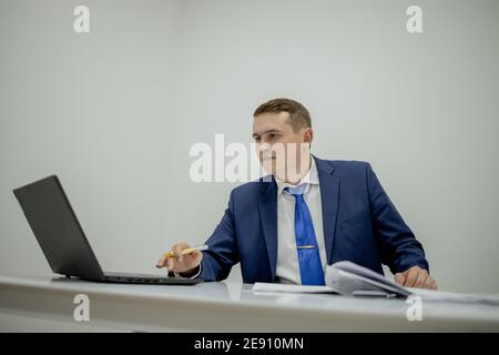 Young business man working at home with laptop and papers on desk Stock Photo