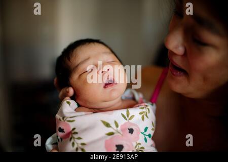 Precious newborn baby with open mouth held by loving mother Stock Photo