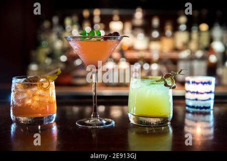 Three colorful fall-inspired cocktails on bar top in cozy bar interior Stock Photo