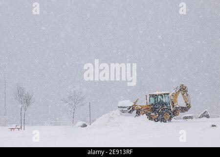 Tractor removing snow in village in winter Stock Photo