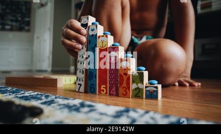 Child on the floor using colorful number blocks with animal faces to learn sequential ordering. Stock Photo