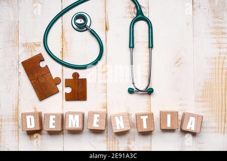 Word DEMENTIA with puzzle pieces and stethoscope on white wooden background Stock Photo