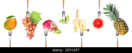 Different fruits impaled on forks against white background Stock Photo