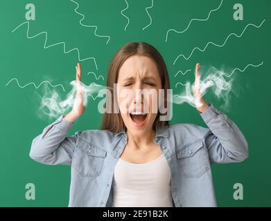 Angry young woman with steam coming out of ears on color background Stock Photo