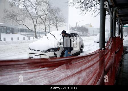 A man clears the snow off his car near the UN Building.The first nor'easter of 2021 has pummelled areas of the northern and central east coast including New York City, with over a foot of snow. Public transportation has been operating at a reduced schedule and coronavirus vaccination sites have been shut down, this possibly being the biggest storm surge since Superstorm Sandy in 2012. Stock Photo
