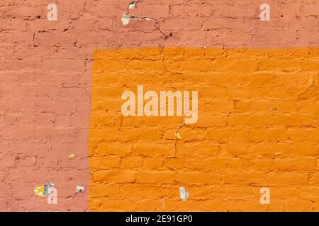 Old deteriorating rusty red color painted brick wall texture background, showing significant erosion from natural aging Stock Photo