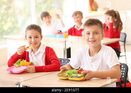 Pupils having healthy lunch in classroom Stock Photo