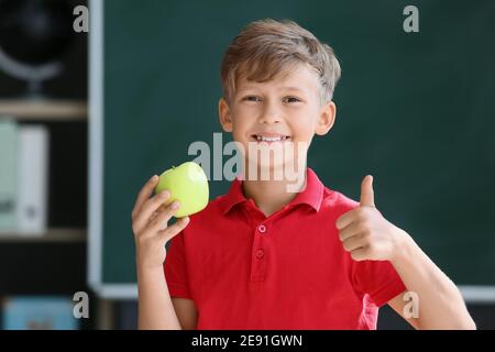 Schoolboy with apple against blurred background in school Stock Photo