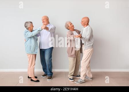 Senior couples dancing near light wall Stock Photo