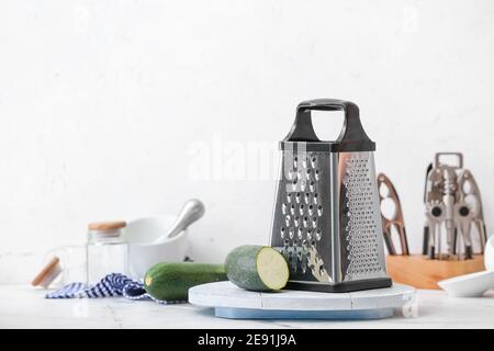 Metal grater and zucchini on table Stock Photo