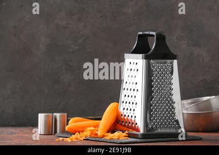 Metal grater and carrots on dark background Stock Photo