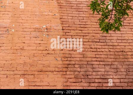 Shabby chic old deteriorating rusty red color brick wall texture background, showing significant erosion and showing faint tree shadows Stock Photo