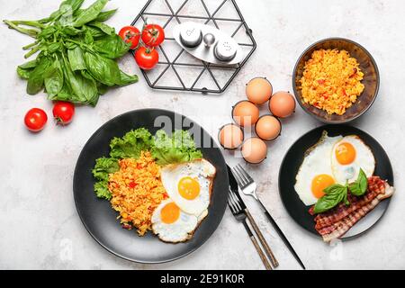 Plates with tasty eggs, bacon and rice on light background Stock Photo