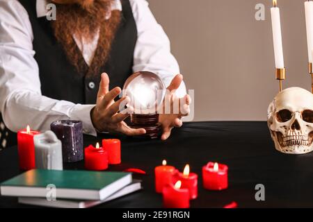 Male fortune teller with crystal ball at table Stock Photo