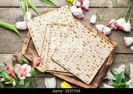 Jewish flatbread matza for Passover and flowers on wooden background Stock Photo