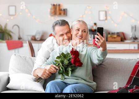 Mature couple taking selfie while celebrating Valentine's Day at home Stock Photo