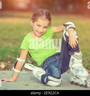 Little girl on roller skates sitting in park Stock Photo