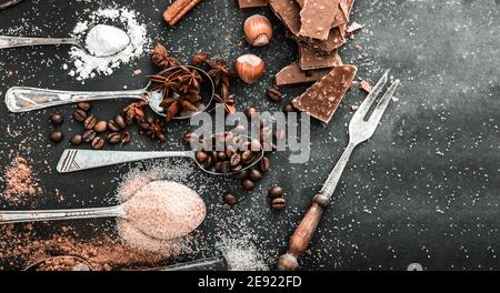 Sweet powdered ingredients in a spoon and chocolate on a table black Stock Photo