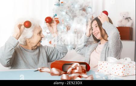 Smiling granddaughter ang grandma playing with decorative balls at Christmas Stock Photo