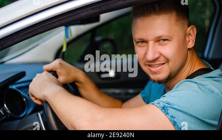 Young attractive man in white car, outdoors Stock Photo