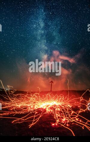 Glowing sparks of night fire under sky full of stars Stock Photo