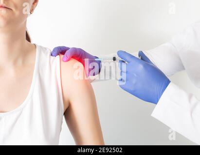 The doctor makes a girl patient an injection blockade in the shoulder joint to relieve muscle tension and pain. Treatment concept for joint arthrosis Stock Photo